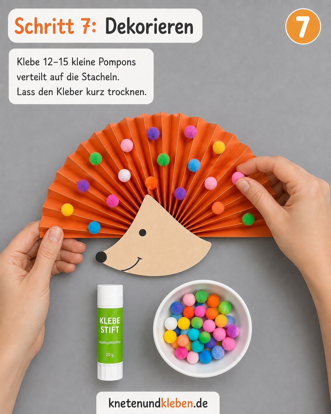 Bunte Pompons werden auf die Stacheln des Papierfächers geklebt, während er trocknet