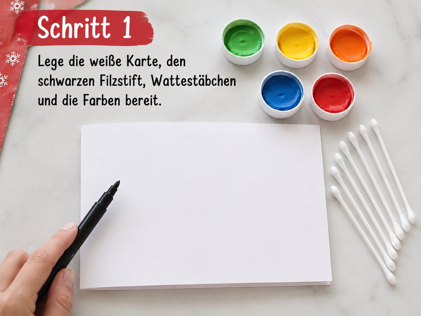 Weiße Karte, Filzstift, Wattestäbchen und Farbtöpfchen für die Weihnachtskarte mit Lichterkette bereitgelegt
